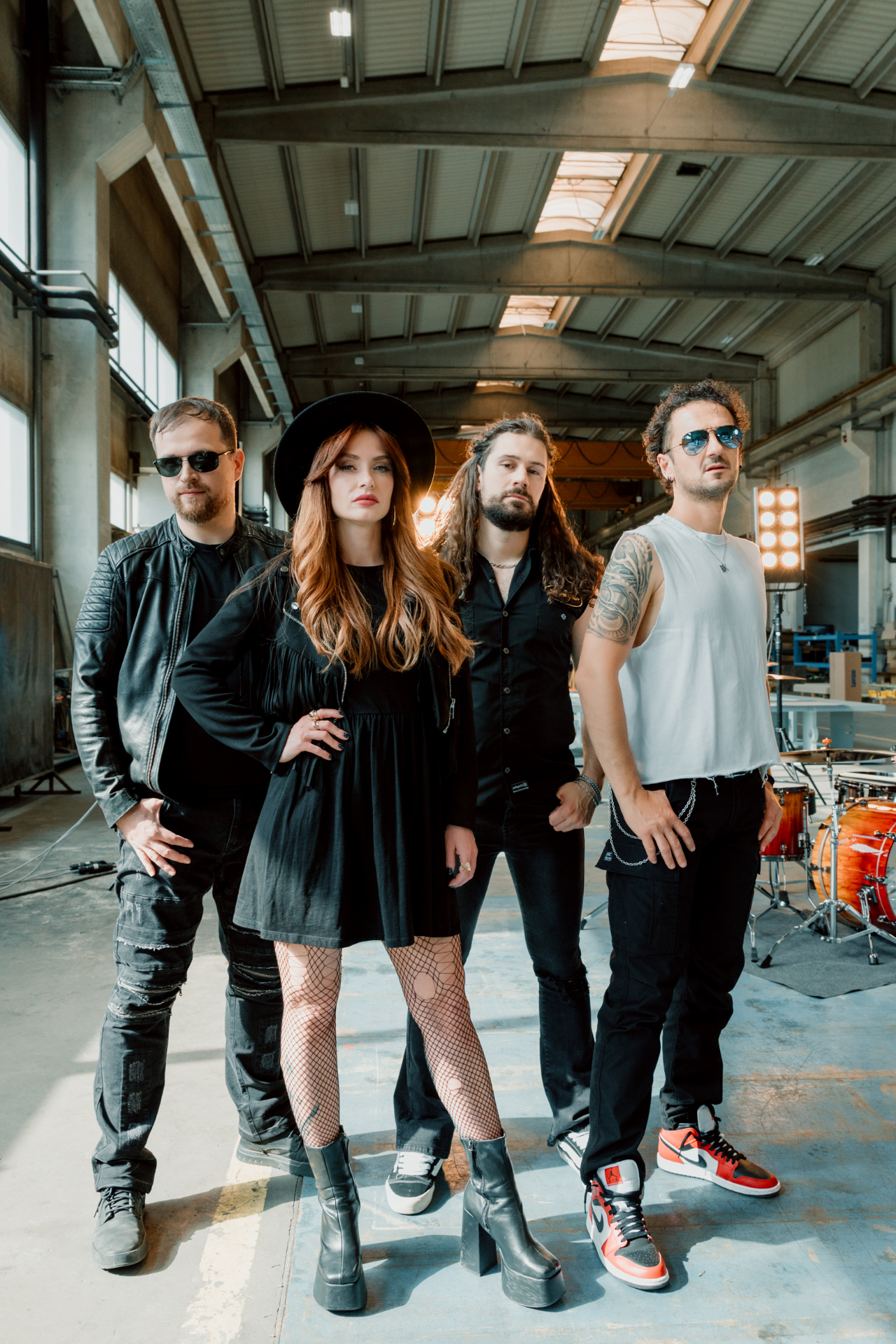 Grit Cathedral standing in a warehouse setting for a full-length promo photo.