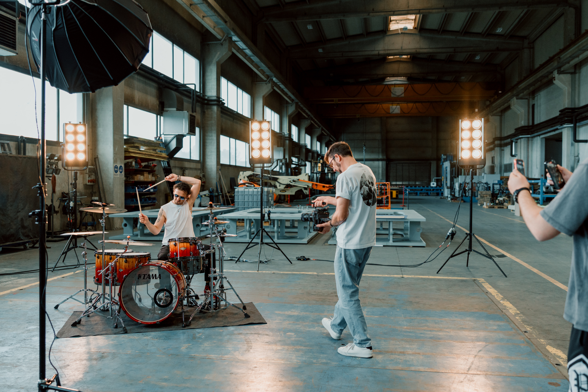 Behind-the-scenes view of the band video shoot with lights, camera crew and drum kit.