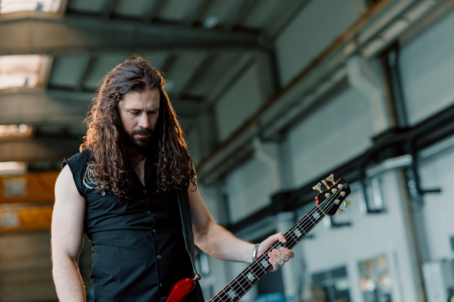 Luka holding a red bass guitar in a close portrait on the video set.