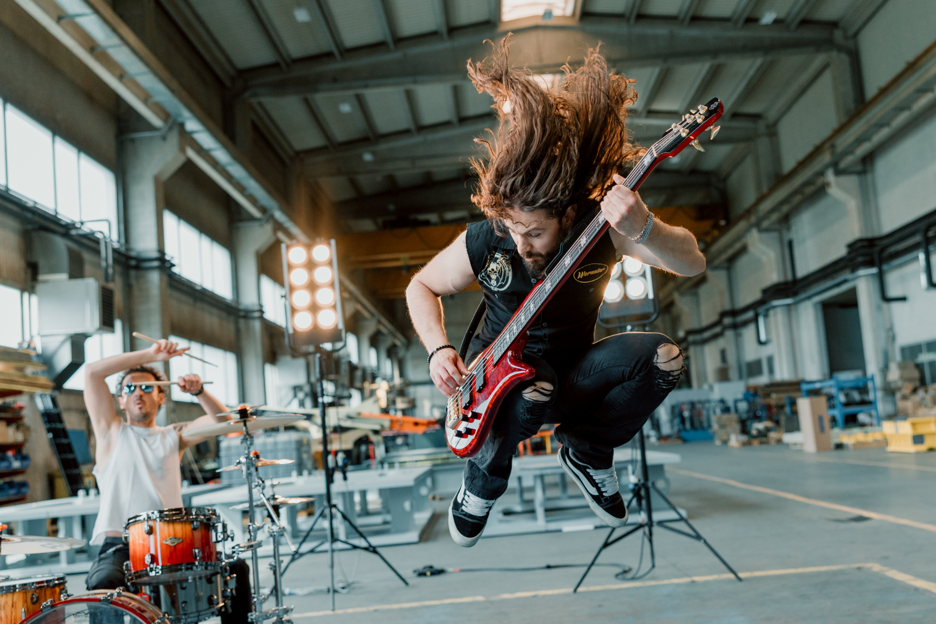 Luka jumping with his bass guitar while Jure plays drums in the background.